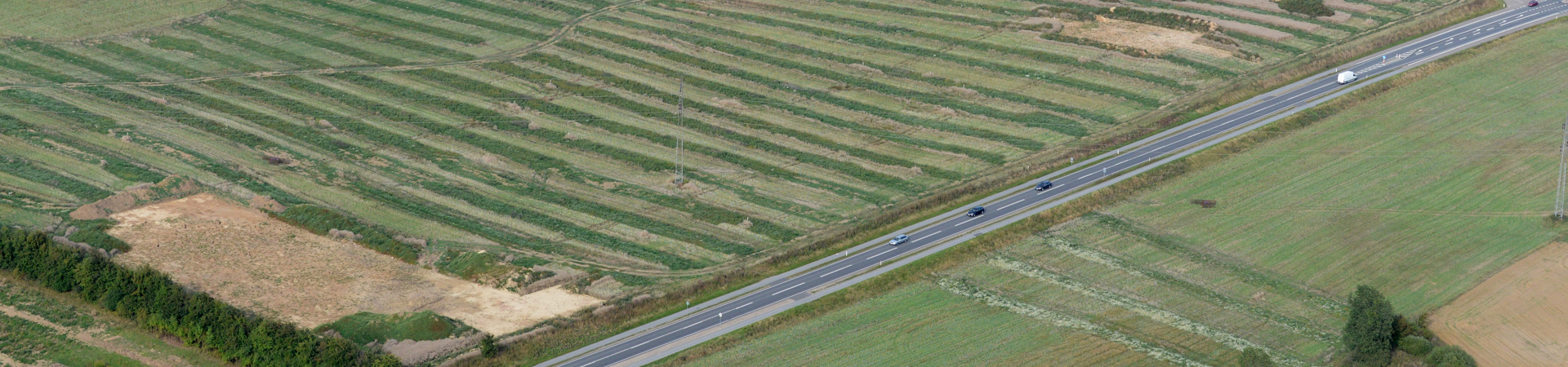 Genrefoto taget med drone af en landevej i Jylland, der løber med marker på begge sider Genrefoto taget med drone af en landevej i Jylland, der løber med marker på begge sider